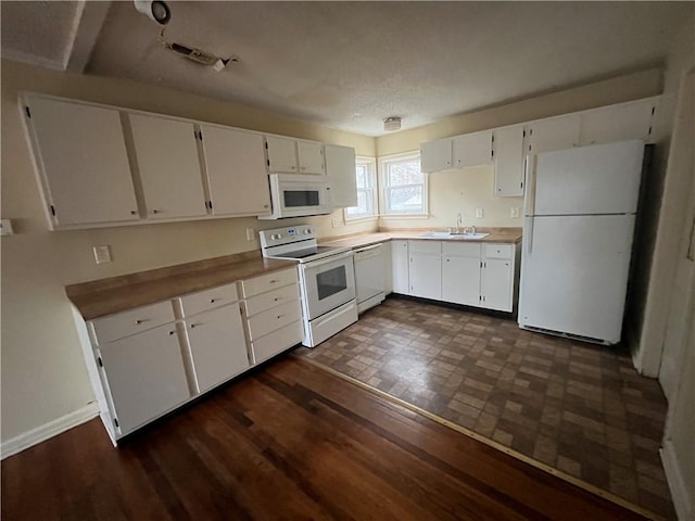 kitchen with white cabinetry, white appliances, dark hardwood / wood-style flooring, and sink