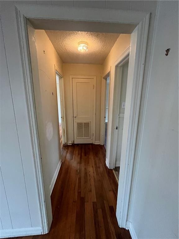 corridor with dark wood-type flooring and a textured ceiling