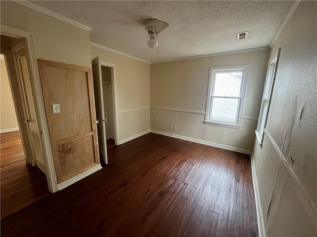 unfurnished bedroom featuring ceiling fan, crown molding, dark wood-type flooring, and a textured ceiling