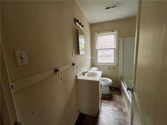 full bathroom featuring enclosed tub / shower combo, vanity, toilet, and a textured ceiling