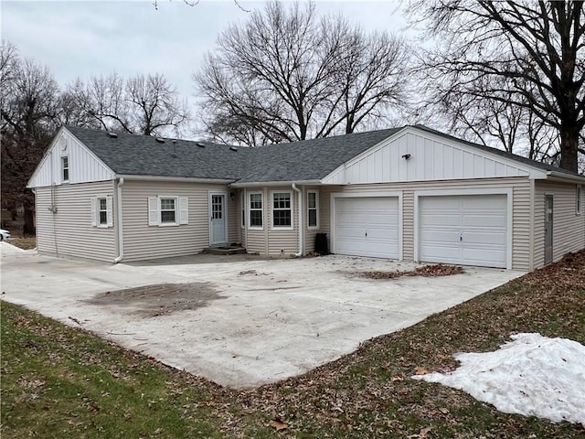 back of property with board and batten siding, concrete driveway, a garage, and a shingled roof