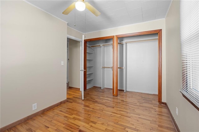 unfurnished bedroom featuring multiple closets, ceiling fan, ornamental molding, and light wood-type flooring