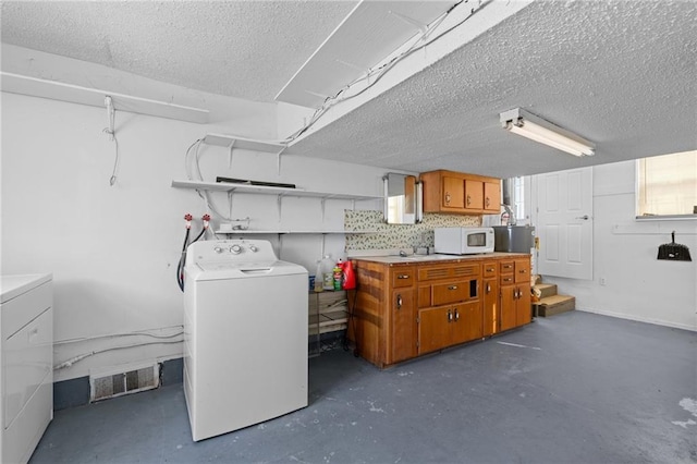 below grade area with visible vents, independent washer and dryer, and a textured ceiling