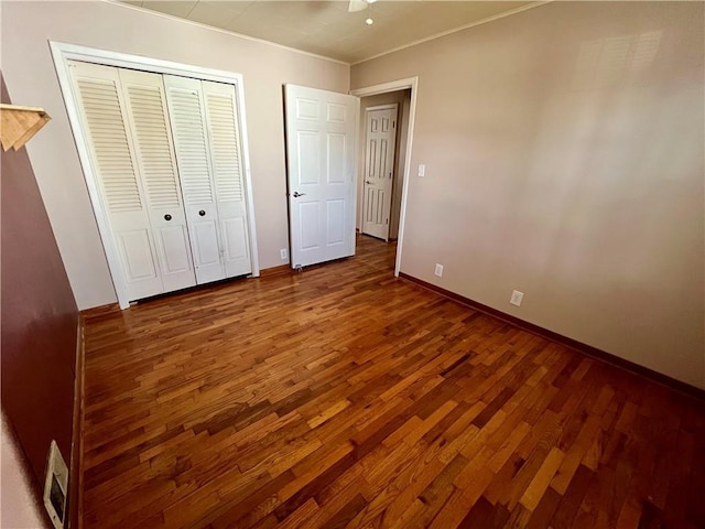 unfurnished bedroom with a closet, baseboards, and wood finished floors