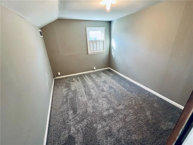 interior space featuring carpet flooring, lofted ceiling, and baseboards