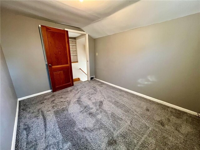 carpeted spare room with baseboards and lofted ceiling