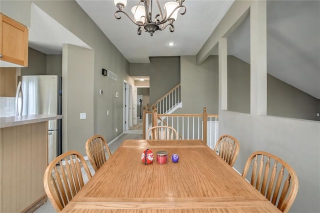 dining room featuring a chandelier, baseboards, and vaulted ceiling