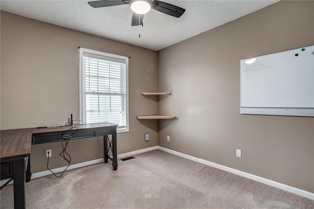 office area featuring visible vents, a textured ceiling, baseboards, light colored carpet, and ceiling fan