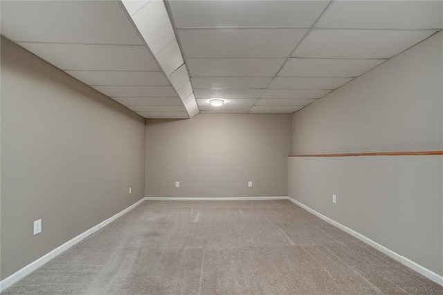 finished below grade area featuring carpet flooring, a paneled ceiling, and baseboards