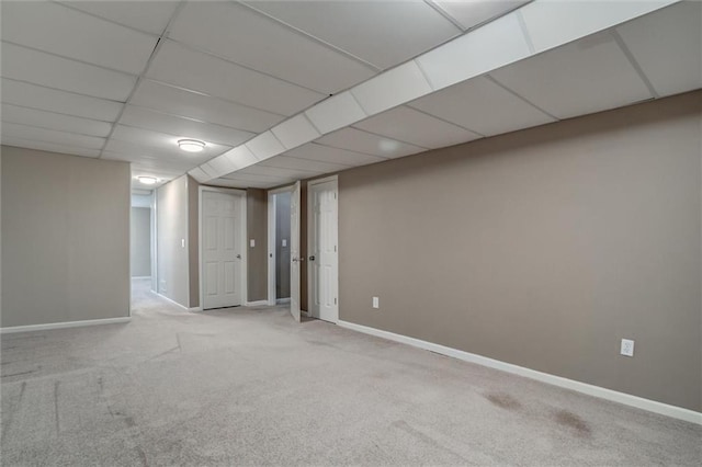 finished basement with carpet flooring, a paneled ceiling, and baseboards