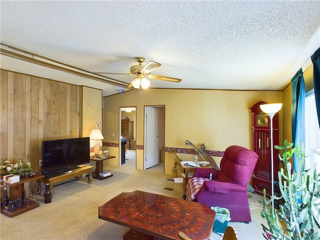 carpeted living room with ceiling fan, a textured ceiling, and wood walls