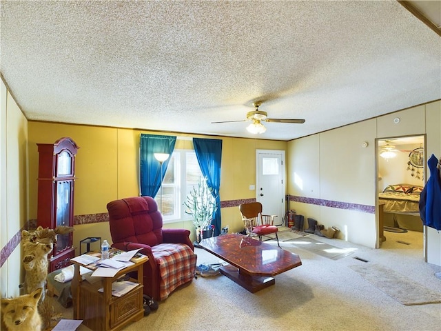 sitting room with ceiling fan, carpet floors, and a textured ceiling