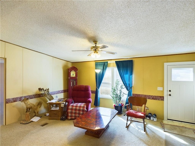 living area with ceiling fan, carpet floors, a textured ceiling, and a wealth of natural light