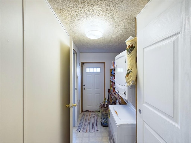 laundry area featuring stacked washer and clothes dryer and a textured ceiling