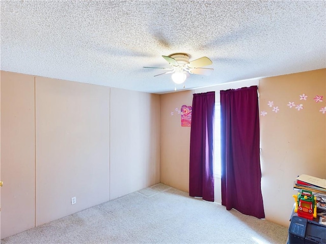 unfurnished room with ceiling fan, light carpet, and a textured ceiling