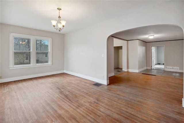 empty room featuring wood-type flooring and a chandelier