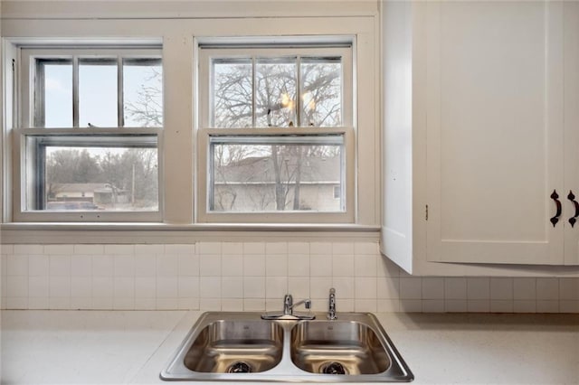 interior details featuring sink, decorative backsplash, and white cabinets