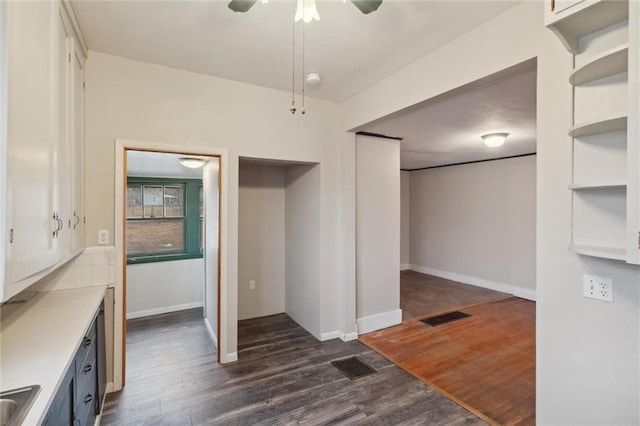 interior space with dark wood-type flooring, white cabinetry, ceiling fan, and sink