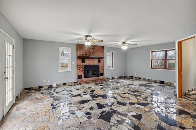 unfurnished living room featuring a brick fireplace, a wealth of natural light, and ceiling fan