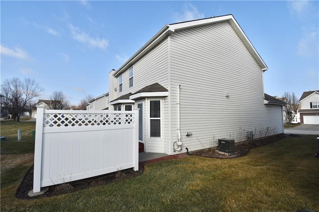 view of side of property featuring cooling unit and a yard