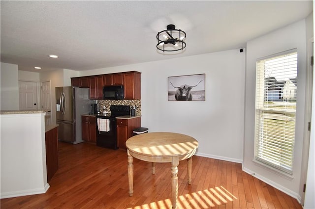 kitchen featuring backsplash, plenty of natural light, black appliances, and light hardwood / wood-style floors