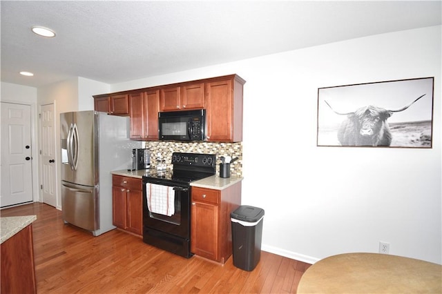 kitchen featuring backsplash, light hardwood / wood-style flooring, and black appliances