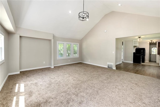 unfurnished living room featuring carpet, a healthy amount of sunlight, and high vaulted ceiling