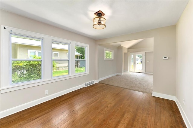 spare room with hardwood / wood-style flooring and vaulted ceiling