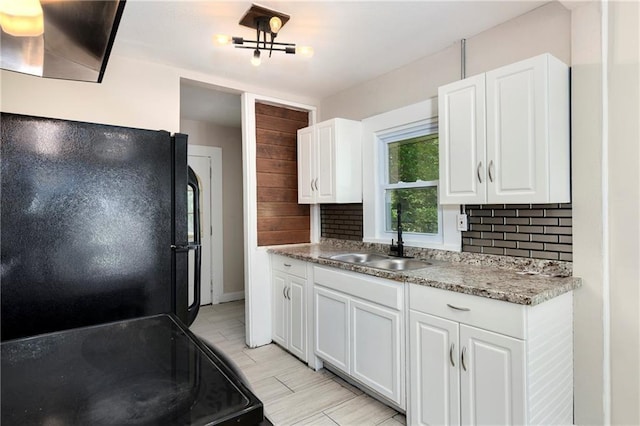 kitchen with tasteful backsplash, white cabinetry, sink, and black appliances