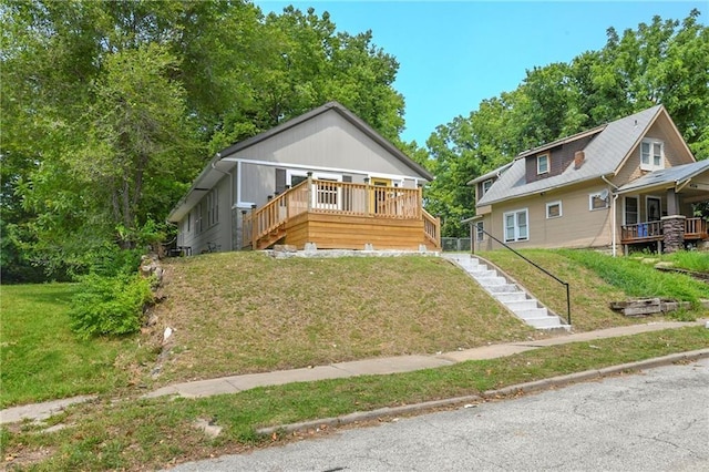 bungalow featuring a wooden deck and a front lawn