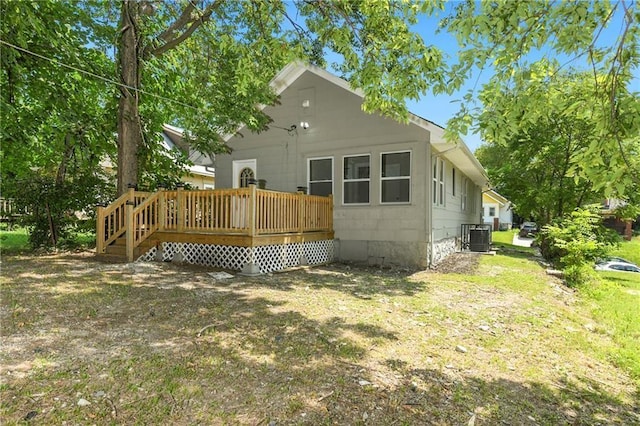 back of property with a wooden deck, a yard, and cooling unit