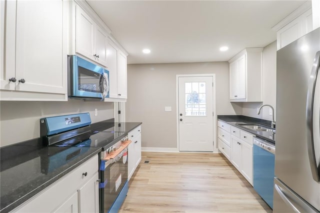 kitchen featuring sink, dark stone counters, stainless steel appliances, light hardwood / wood-style floors, and white cabinets