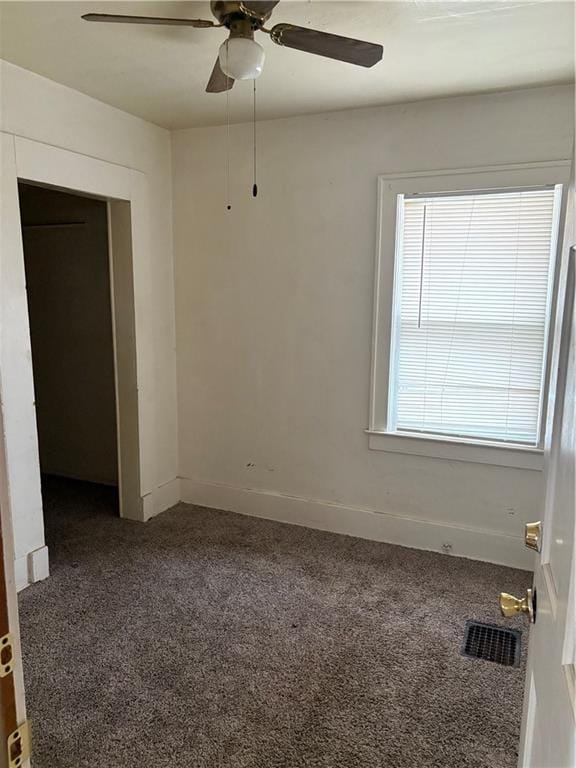 empty room with dark carpet and ceiling fan