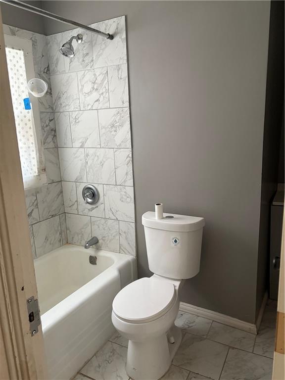 bathroom with toilet and tiled shower / bath