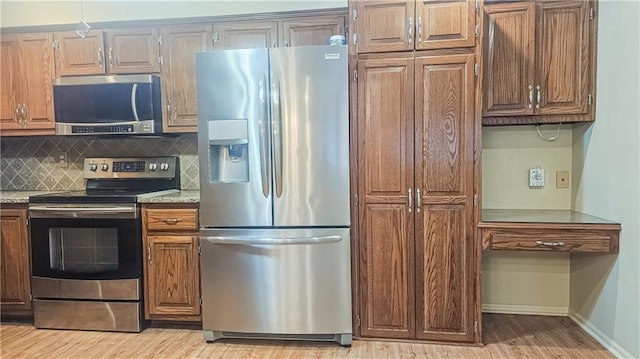 kitchen featuring backsplash, stainless steel appliances, light stone countertops, and light wood-type flooring