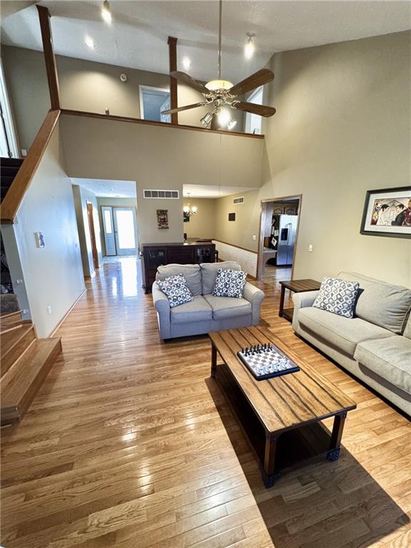 living room with ceiling fan, stairway, wood finished floors, and visible vents