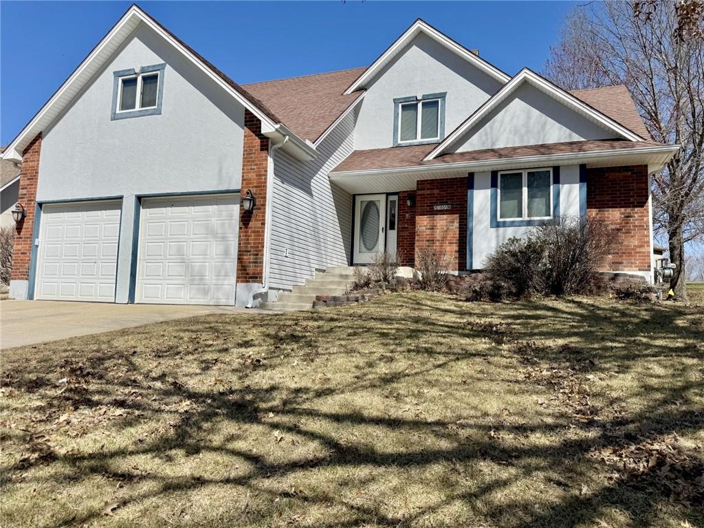 1605 Roanoke Dr, Warrensburg, MO 64093 - view of front facade with driveway, stucco siding, a front lawn, a garage, and brick siding