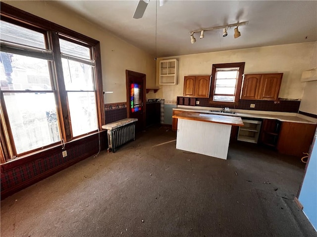 kitchen with sink, a kitchen island, ceiling fan, hanging light fixtures, and radiator