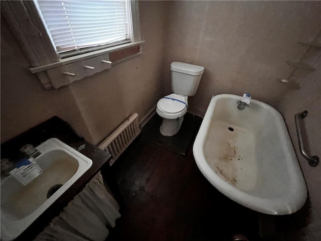 bathroom with sink, toilet, and a tub to relax in