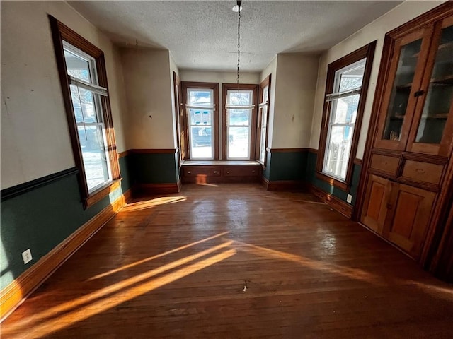 unfurnished dining area with dark hardwood / wood-style flooring and a textured ceiling