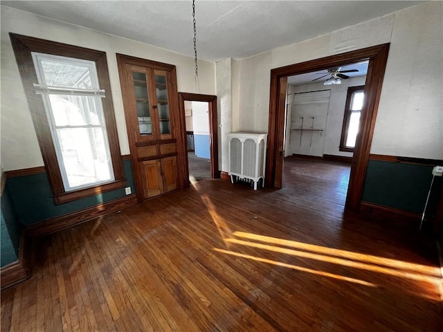 unfurnished dining area featuring radiator and dark hardwood / wood-style flooring