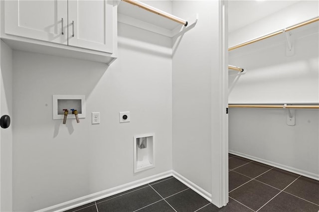 laundry room with electric dryer hookup, dark tile patterned flooring, washer hookup, and cabinets