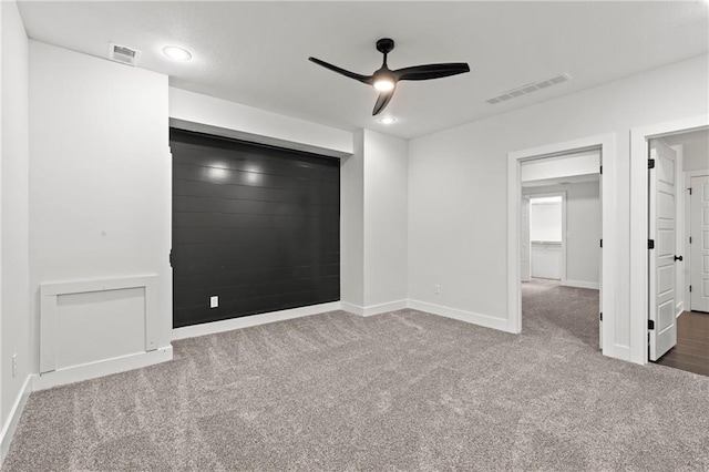 unfurnished bedroom with wooden walls, ceiling fan, and carpet