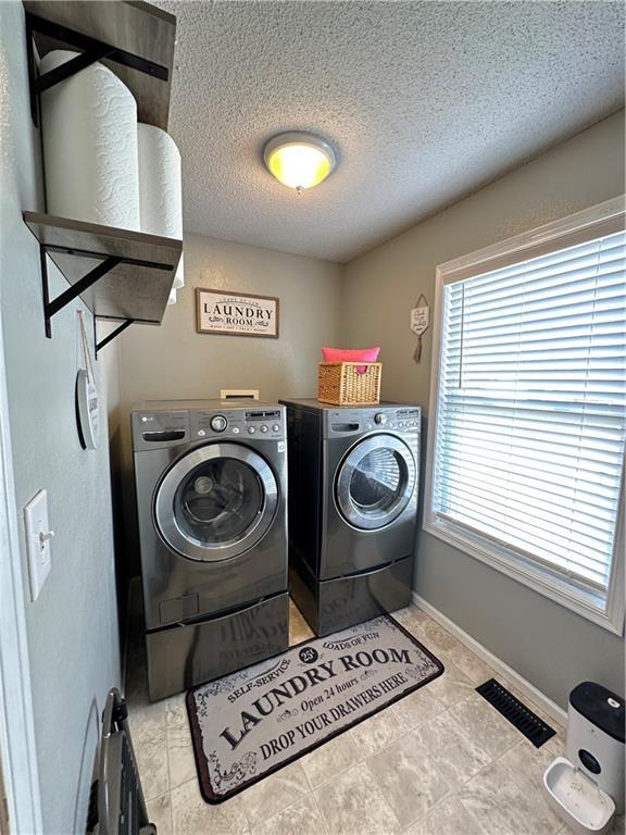 clothes washing area featuring a textured ceiling and washer and clothes dryer