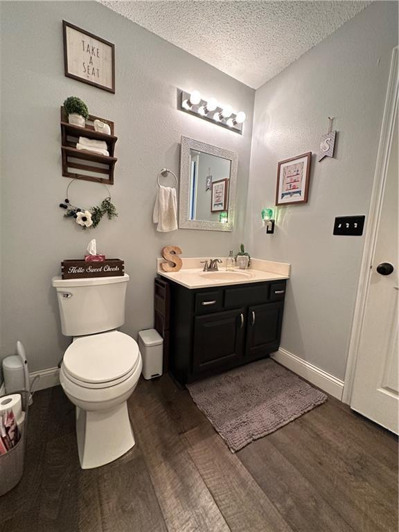 bathroom featuring vanity, hardwood / wood-style floors, toilet, and a textured ceiling