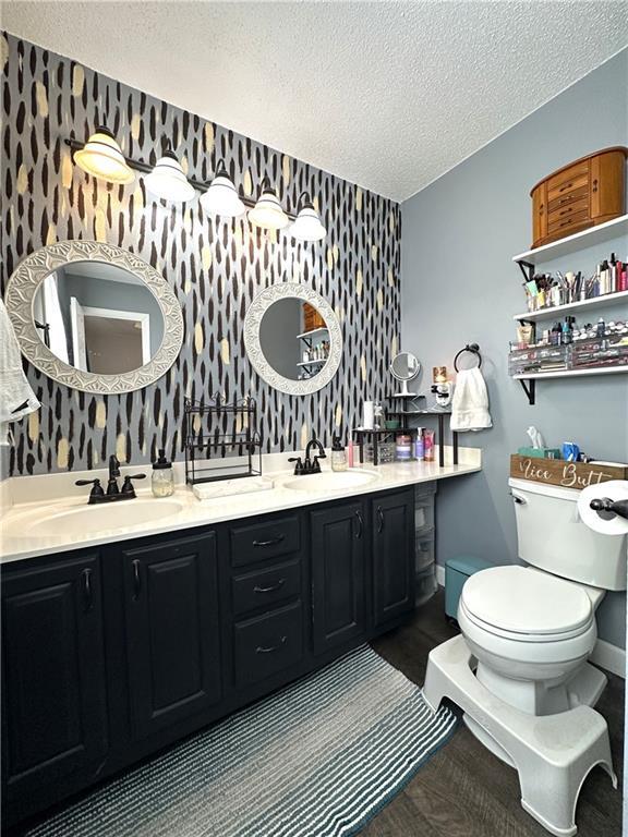 bathroom with vanity, toilet, and a textured ceiling