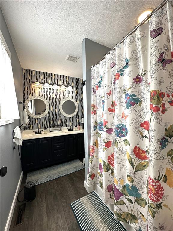 bathroom with vanity, wood-type flooring, a textured ceiling, and walk in shower