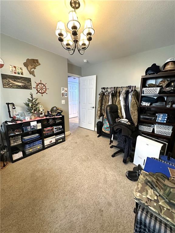 carpeted office space featuring a textured ceiling and an inviting chandelier