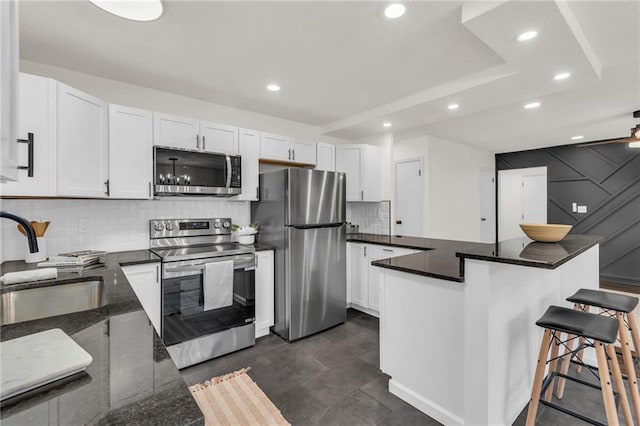 kitchen with sink, white cabinetry, backsplash, stainless steel appliances, and a kitchen breakfast bar