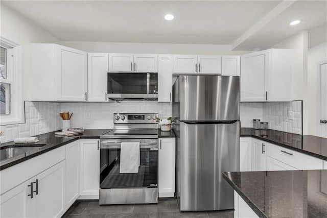 kitchen featuring white cabinetry, decorative backsplash, stainless steel appliances, and dark stone countertops